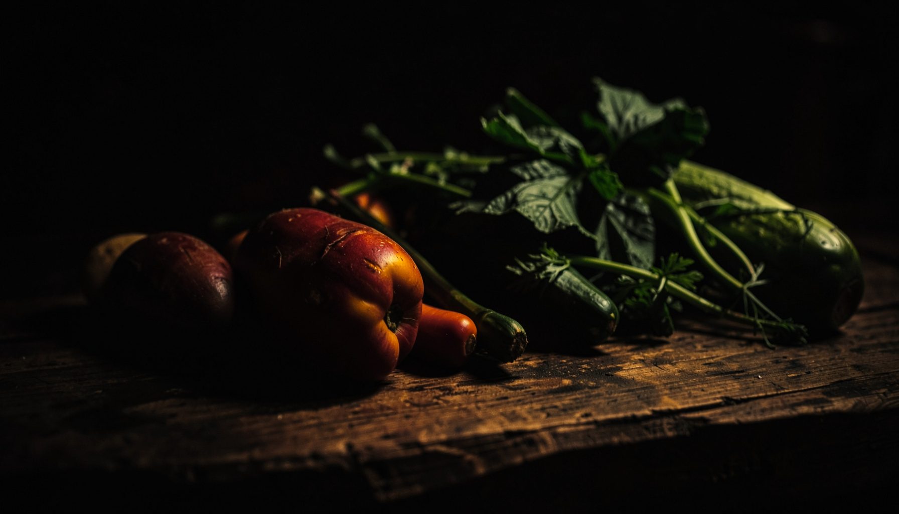 Dark, low-key photograph of fresh produce on a rustic wooden table, deep greens and warm amber tones, moody and atmospheric